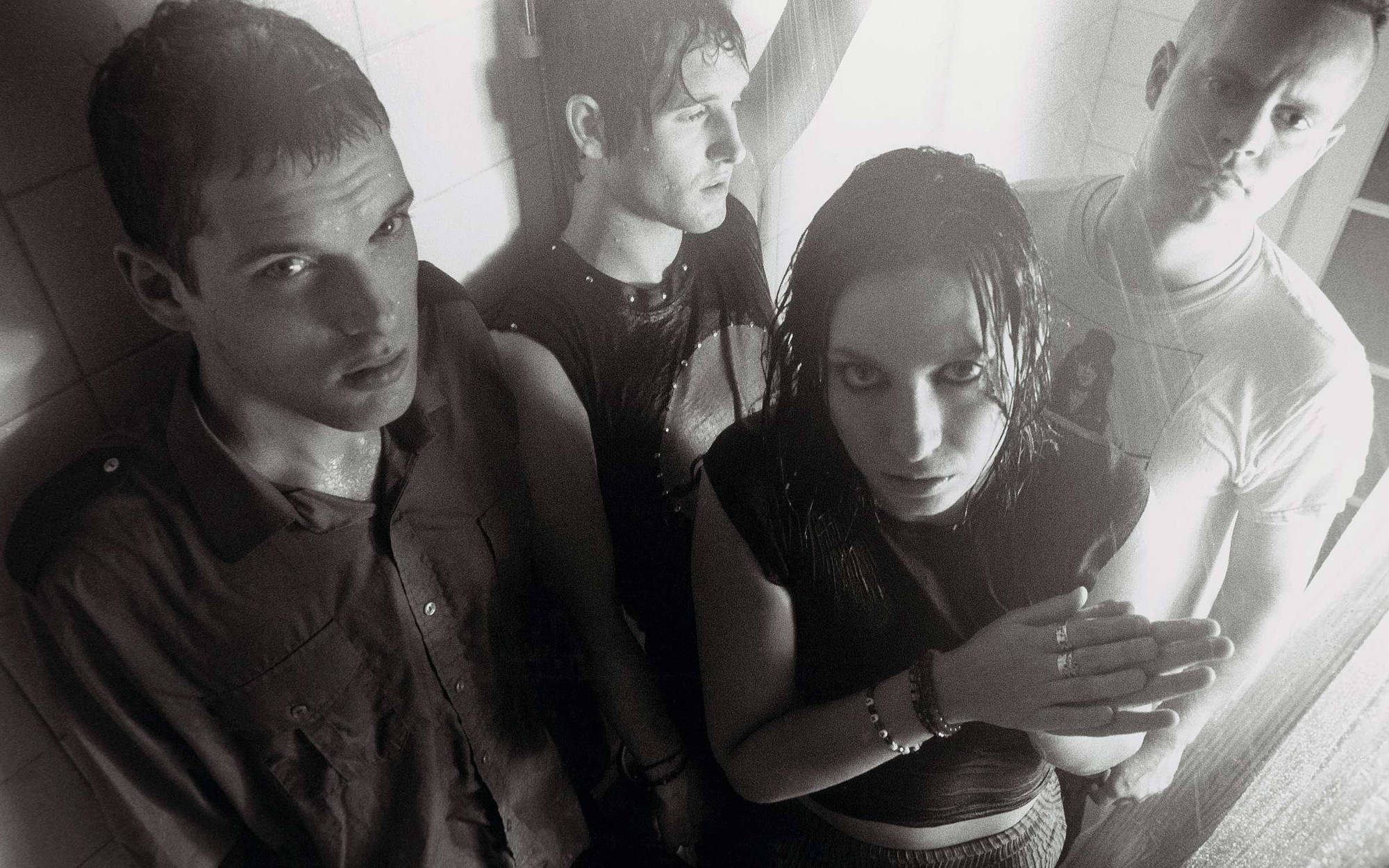 Black and white promo photo of the band in a shower with the water on, taken during the “Free All Angels” era.