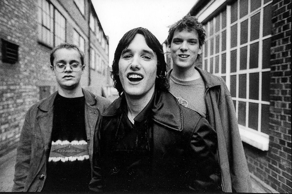 Black and white promo photo of the band laughing to camera taken down an alleyway.